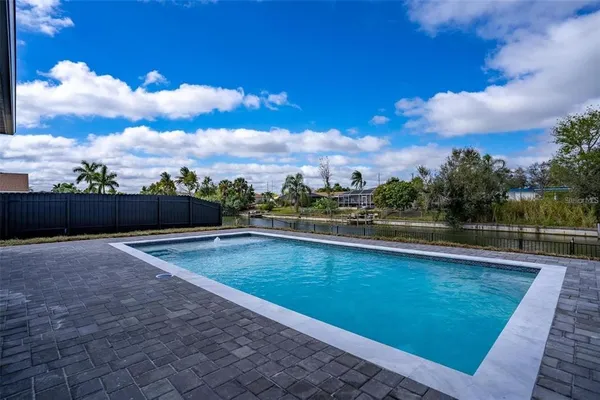 a view of swimming pool with outdoor seating and trees in the background
