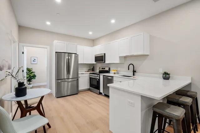 a kitchen with a refrigerator a table and chairs in it