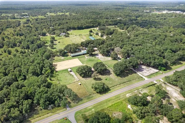 an aerial view of residential houses with outdoor space and trees