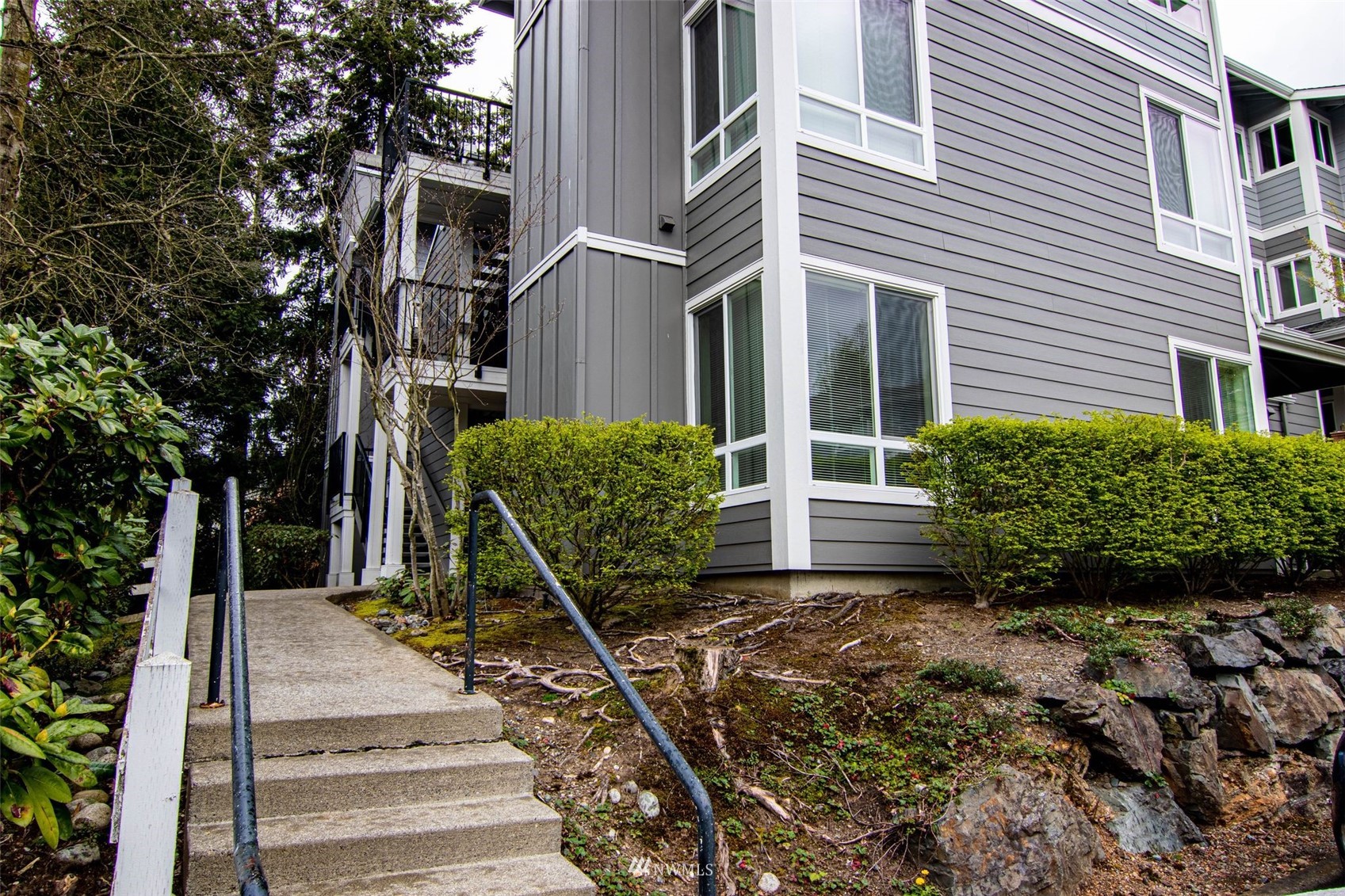 3901 243rd Place Southeast, Unit O102 Bothell, WA 98021 - Photo 4 of 32 a view of a white house with a small yard and plants