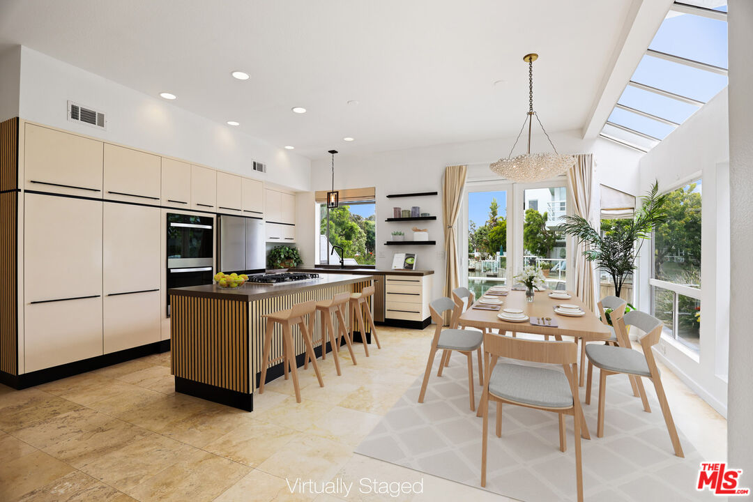 a kitchen with stainless steel appliances kitchen island granite countertop a table chairs and a view of living room