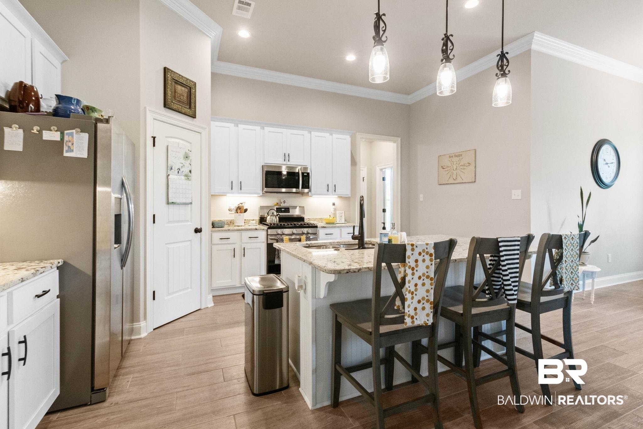 22244 Hibiscus Circle Foley, AL 36535 - Photo 23 of 51 Gourmet kitchen featuring white cabinetry, stainless steel appliances, granite countertops, a central island with bar seating, and wood-finish flooring