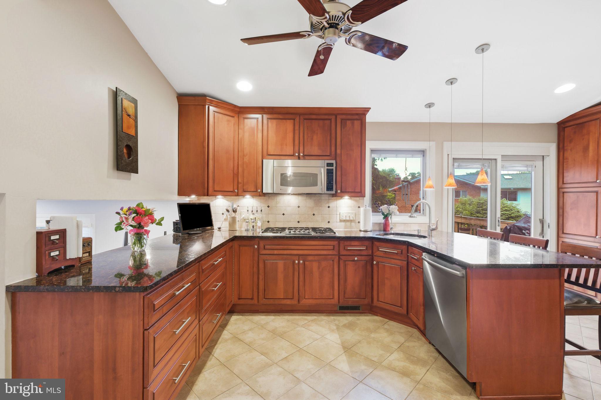 8815 Postoak Road Potomac, MD 20854 - Photo 14 of 45 a kitchen with stainless steel appliances wooden cabinets a sink and a stove