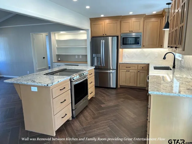 a kitchen with stainless steel appliances granite countertop a stove a refrigerator and a sink