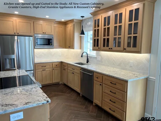 a kitchen with stainless steel appliances granite countertop a sink stove and refrigerator