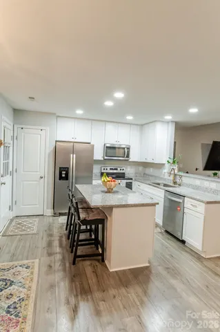 a kitchen with stainless steel appliances granite countertop a table chairs sink refrigerator and cabinets