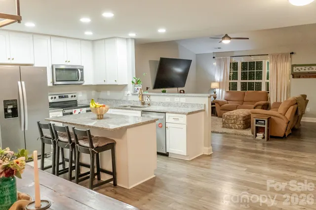 a kitchen with stainless steel appliances granite countertop a stove a sink a microwave a refrigerator and cabinets