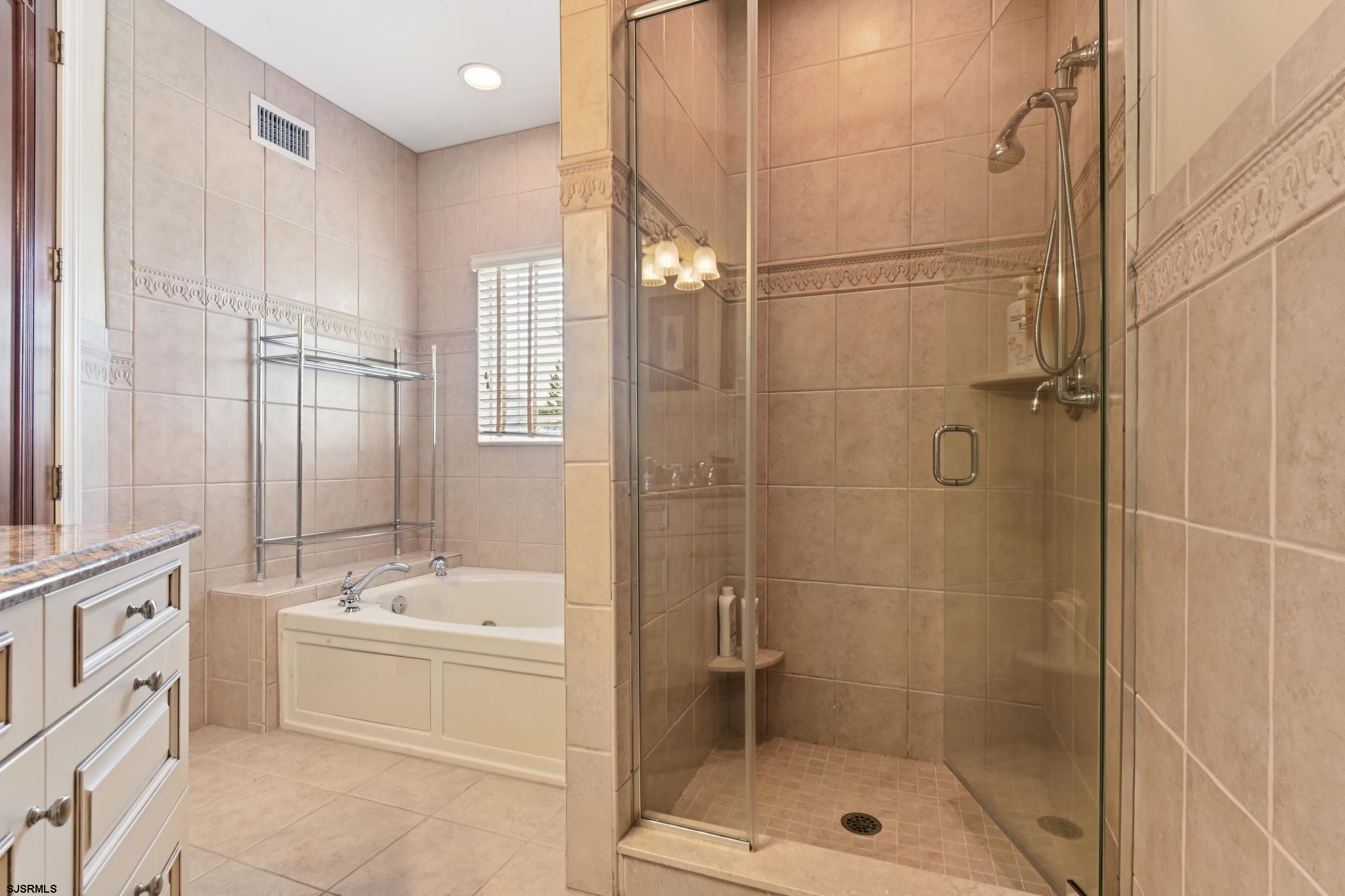 301 Wesley Road Ocean City, NJ 08226 - Photo 11 of 44 a bathroom with a bathtub shower sink vanity and a mirror