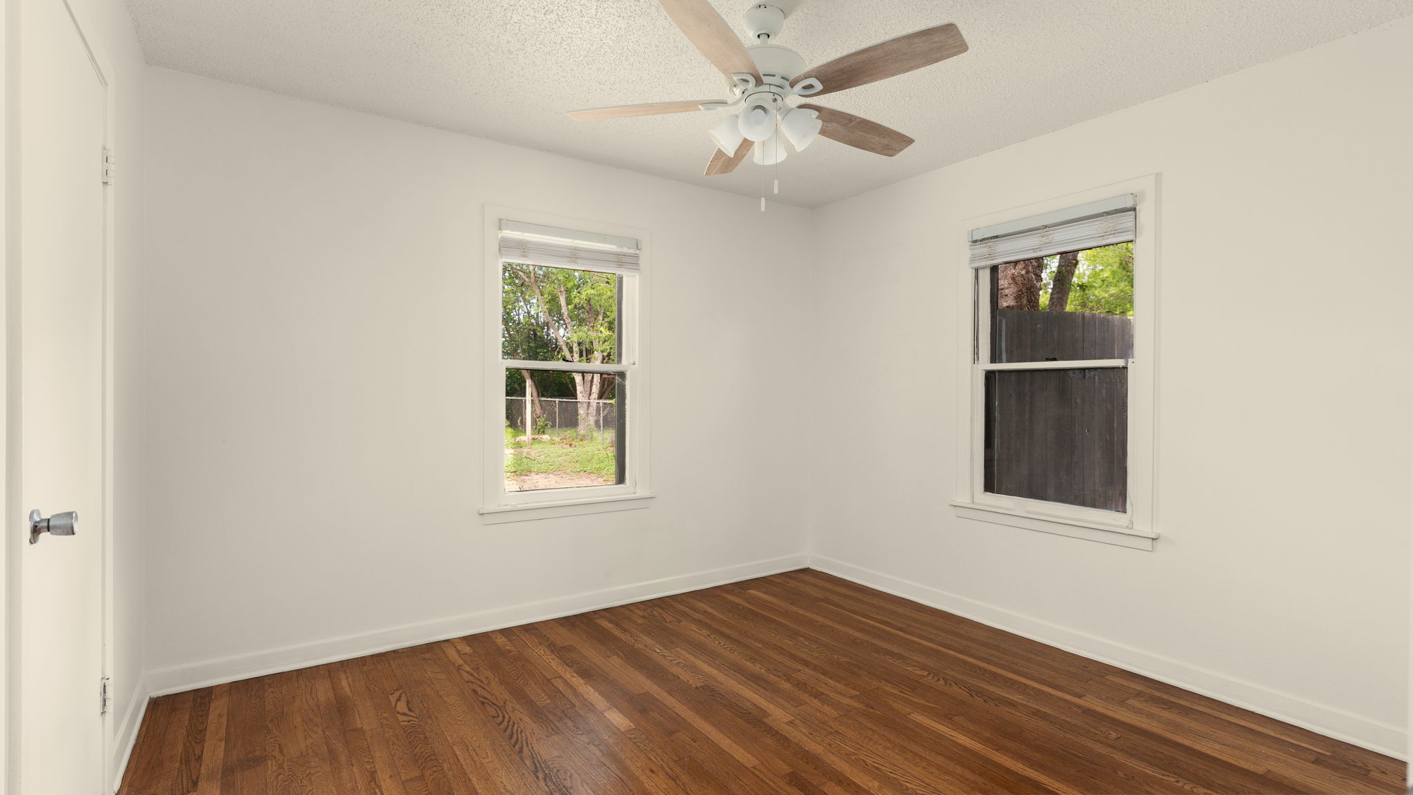 206 East Skyview Road Austin, TX 78752 - Photo 20 of 32 Rich hardwood floors complement this naturally illuminated bedroom with a ceiling fan.