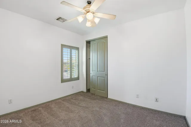 an empty room with a window and a fan