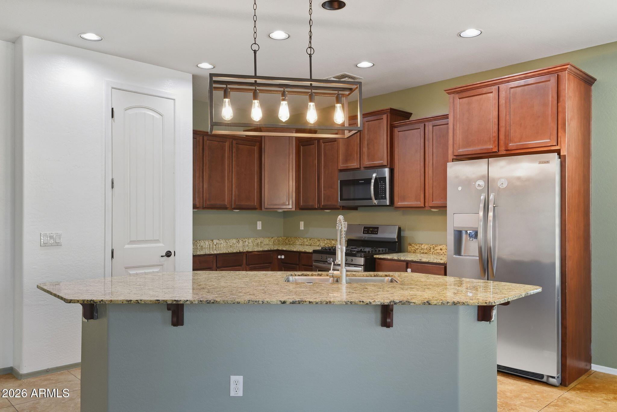 3484 East Mesquite Street Gilbert, AZ 85296 - Photo 4 of 16 a kitchen with stainless steel appliances granite countertop a sink refrigerator and cabinets