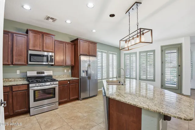 a kitchen with stainless steel appliances granite countertop a stove a refrigerator and a sink