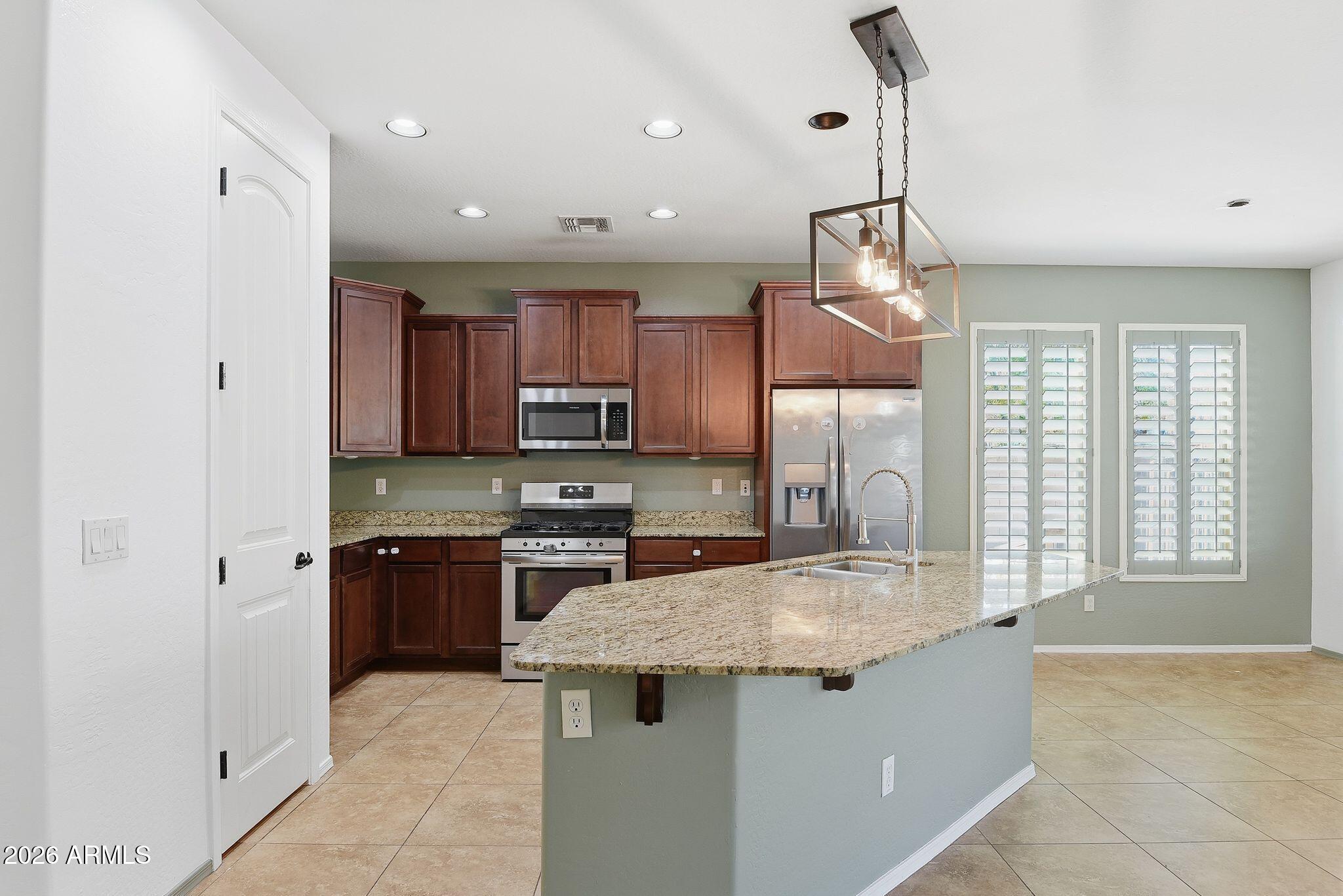 3484 East Mesquite Street Gilbert, AZ 85296 - Photo 8 of 16 a kitchen with stainless steel appliances granite countertop a sink stove and refrigerator