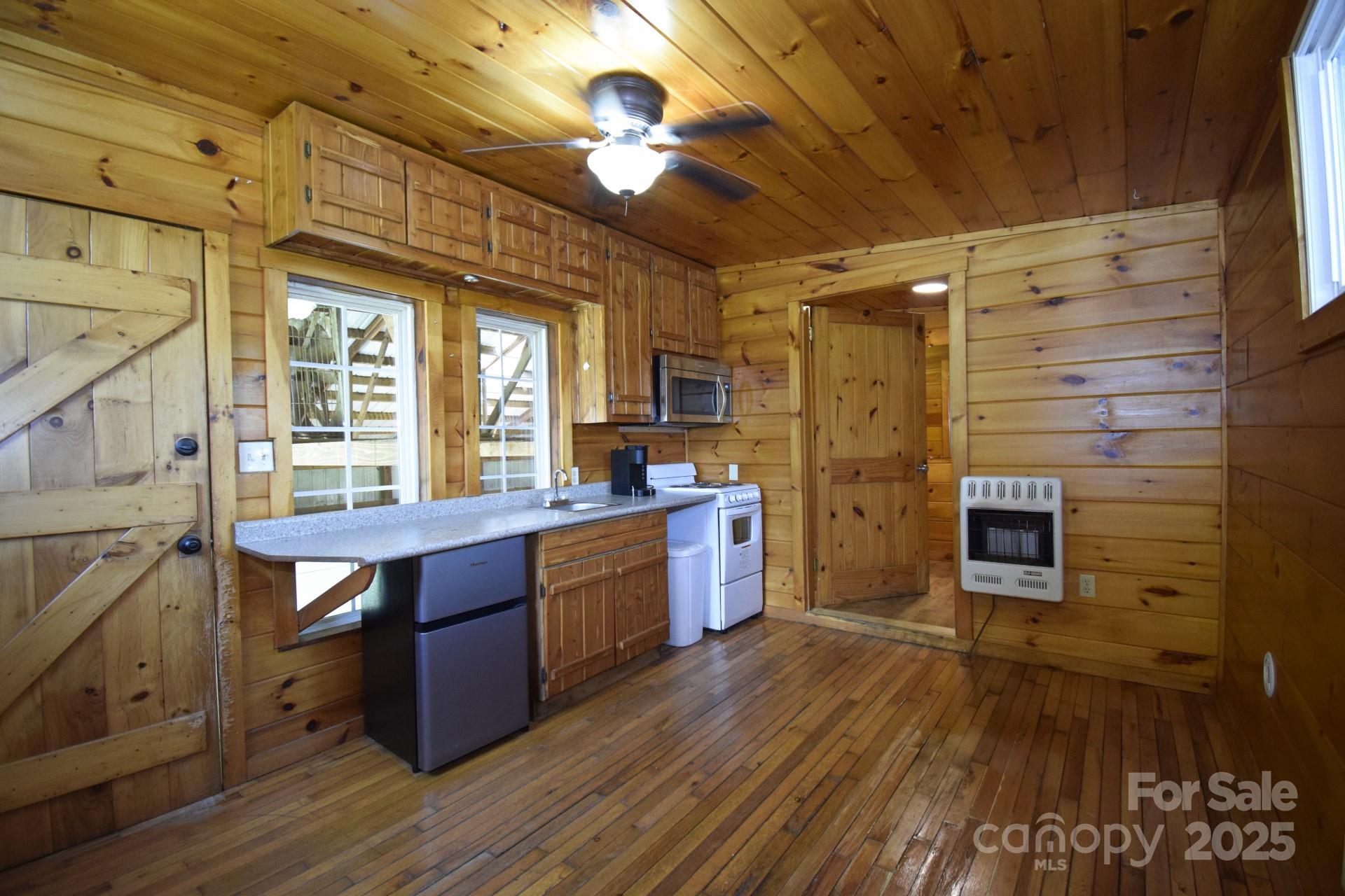 2941 Roby Martin Road Lenoir, NC 28645 - Photo 22 of 47 a kitchen with stainless steel appliances granite countertop a stove a refrigerator a sink with wooden floors and cabinets