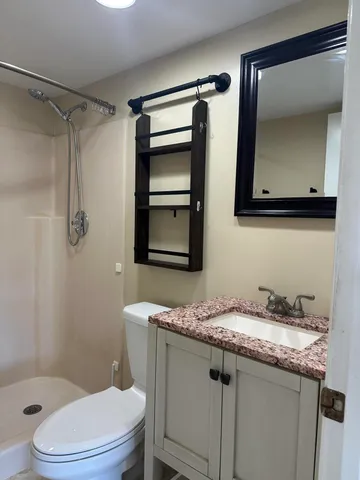 a bathroom with a granite countertop sink toilet and shower