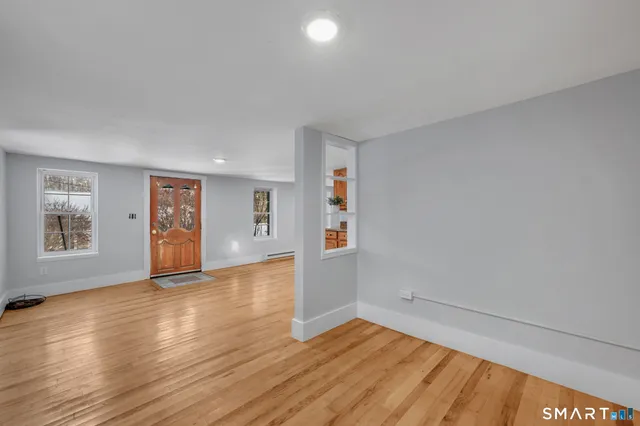 an empty room with wooden floor and windows