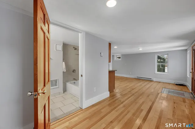 a view of a hallway with wooden floor and a bathroom