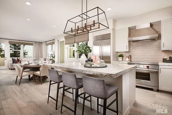 a kitchen with stainless steel appliances granite countertop a table and chairs in it