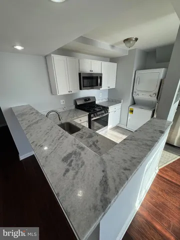 a living room with stainless steel appliances kitchen island granite countertop furniture a sink a stove and a wooden floors