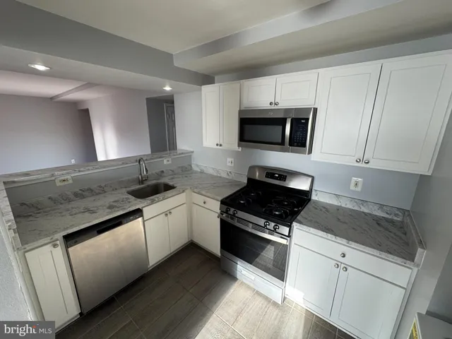 a kitchen with granite countertop white cabinets and black appliances
