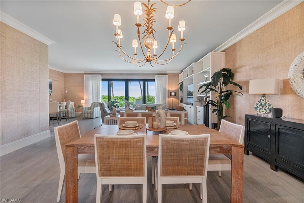 176 South Collier Boulevard, Unit 101 Marco Island, FL 34145 - Photo 12 of 50 a view of a dining room with furniture a chandelier and wooden floor