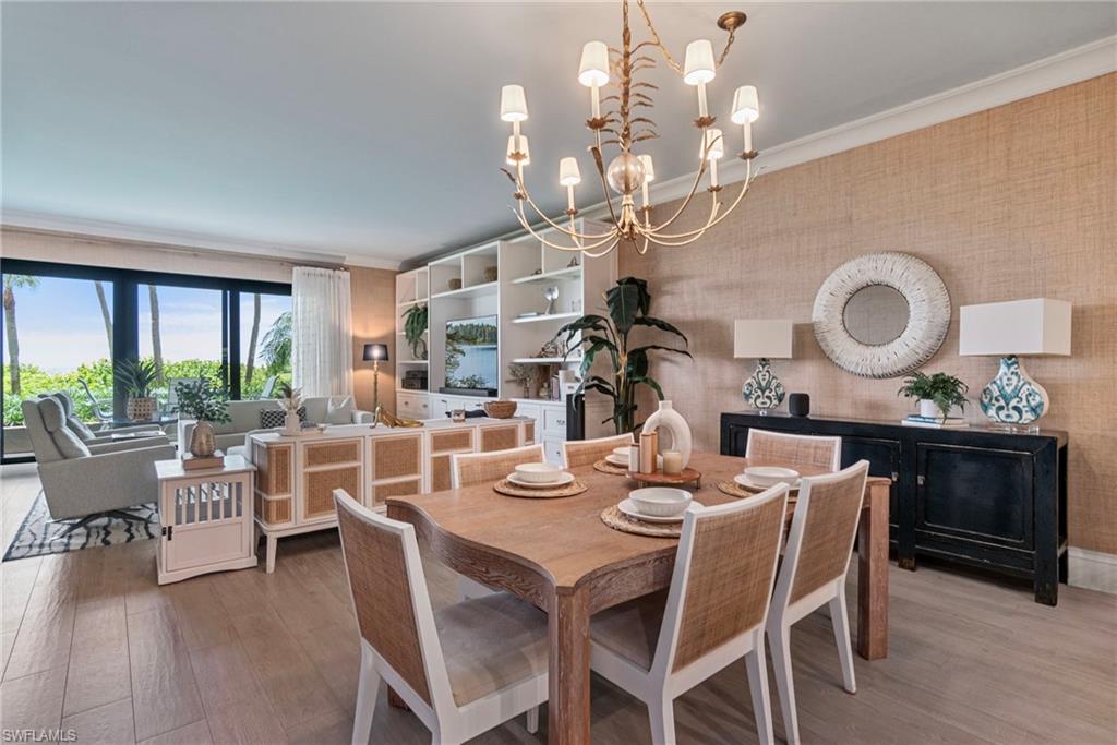 176 South Collier Boulevard, Unit 101 Marco Island, FL 34145 - Photo 14 of 50 a dining room with wooden floor a chandelier a wooden table and chairs
