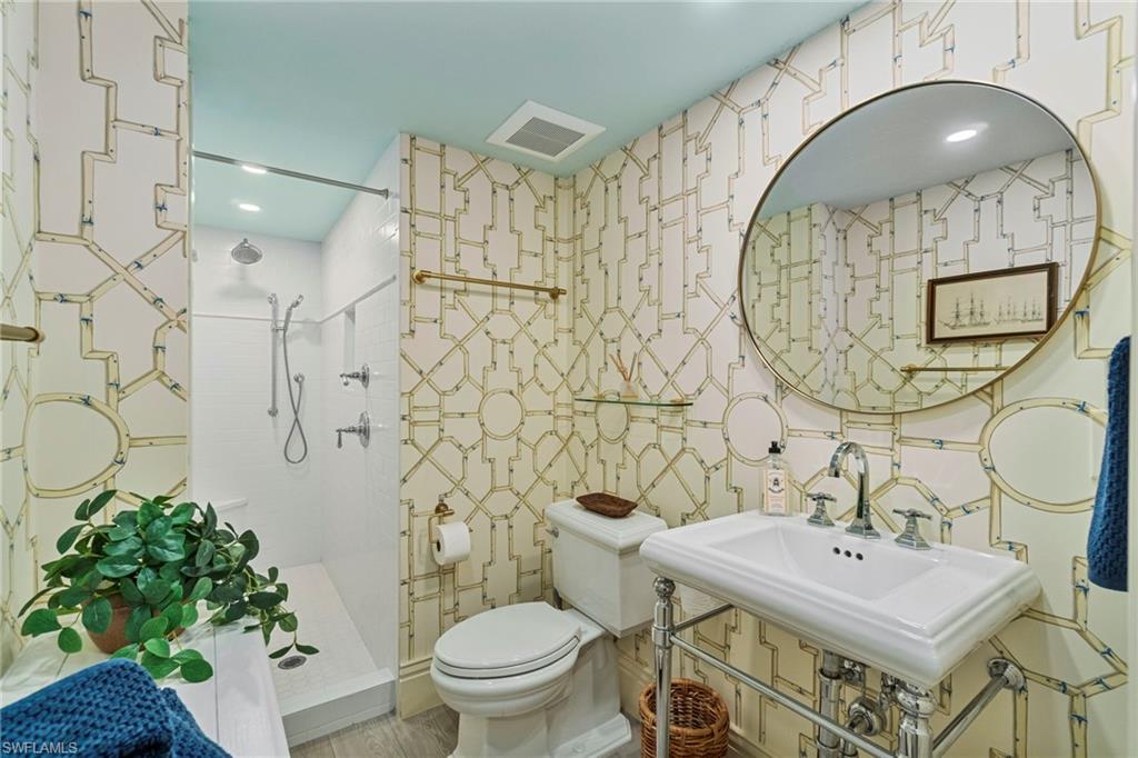 176 South Collier Boulevard, Unit 101 Marco Island, FL 34145 - Photo 37 of 50 a bathroom with a sink a mirror a toilet and a shower