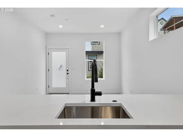 a living room with stainless steel appliances kitchen island granite countertop a sink a stove and white cabinets