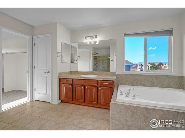 a bathroom with a tub a sink and a large mirror
