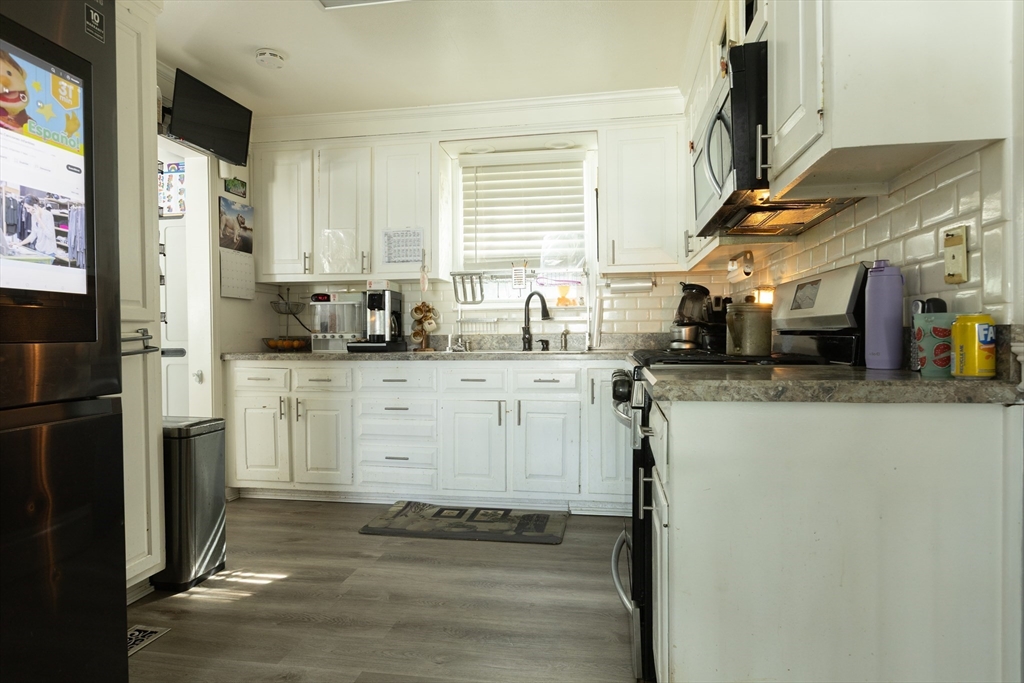 25 Beaconsfield Street Lawrence, MA 01843 - Photo 10 of 36 a kitchen with stainless steel appliances granite countertop a sink a refrigerator a stove and a refrigerator with wooden floor