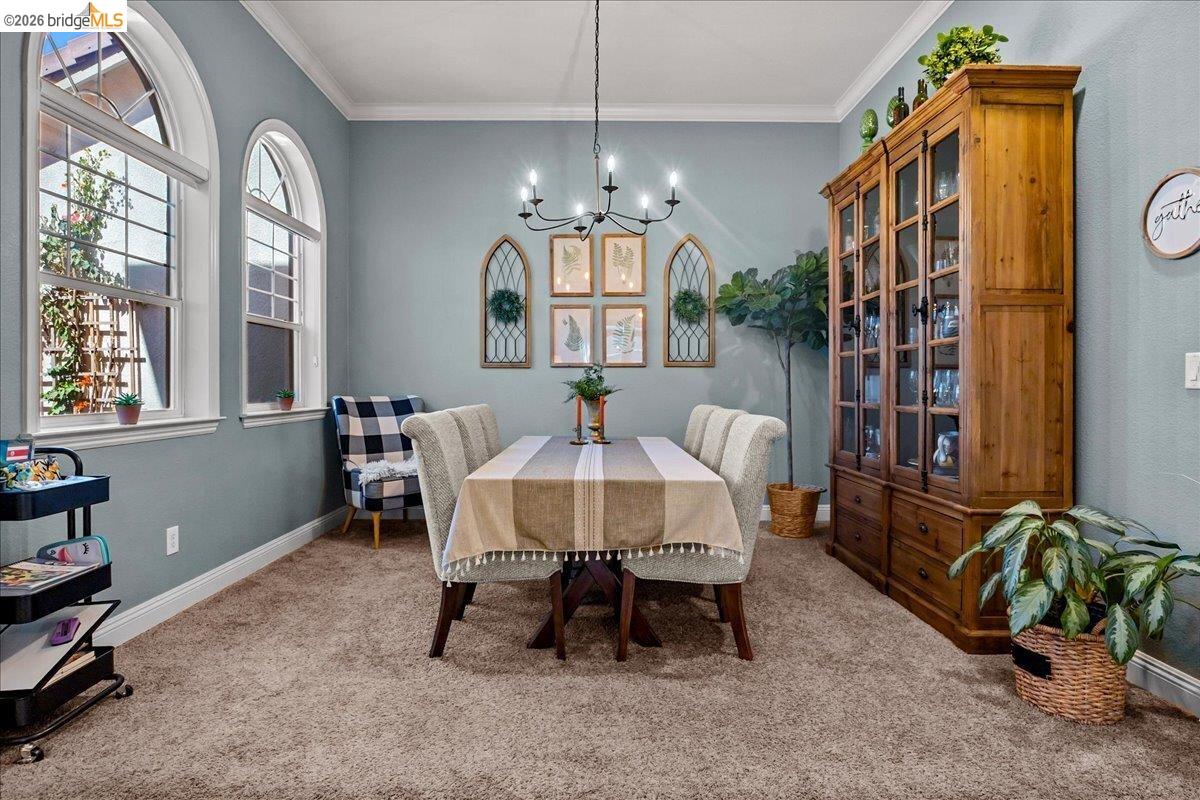 653 Bouma Lane Ripon, CA 95366 - Photo 12 of 39 Arched windows with grid detailing, crown molding, a built-in display cabinet with glass doors, and a black chandelier with candelabra bulbs
