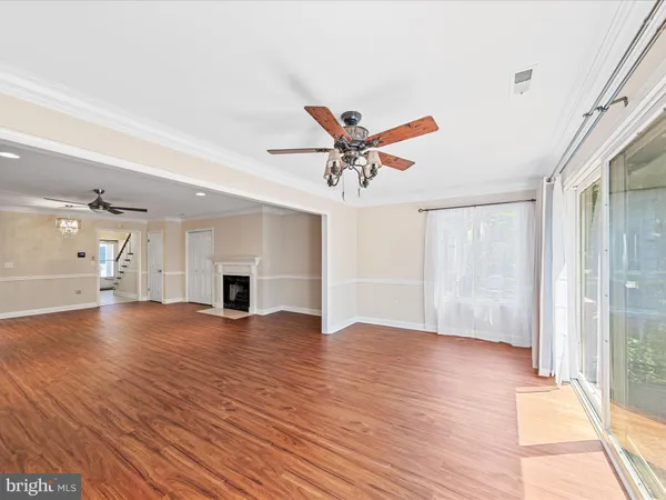 an empty room with wooden floor ceiling fan and windows