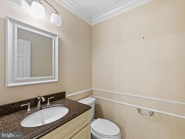 a bathroom with a granite countertop sink mirror vanity and toilet
