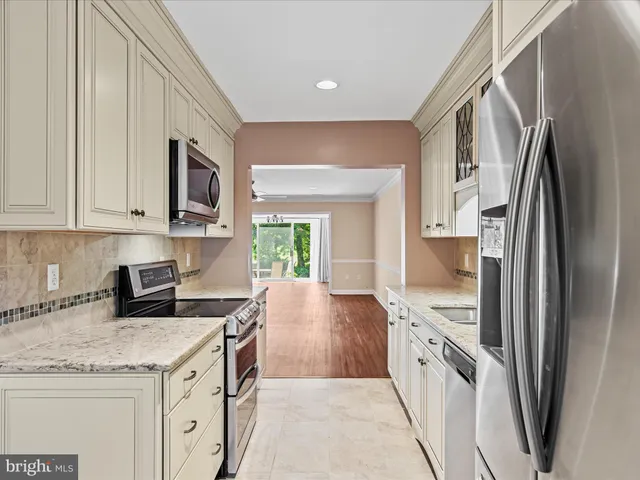 a kitchen with stainless steel appliances granite countertop a refrigerator a stove and a sink