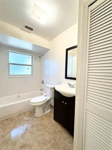 a bathroom with a toilet sink vanity granite and mirror