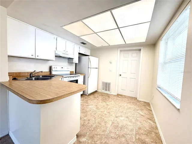 a kitchen with stainless steel appliances granite countertop a sink a stove a refrigerator and white cabinets