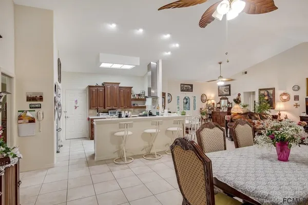 a dining hall with stainless steel appliances kitchen island granite countertop a table chairs and a refrigerator