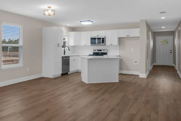 a view of kitchen with stainless steel appliances refrigerator stove top oven and cabinets