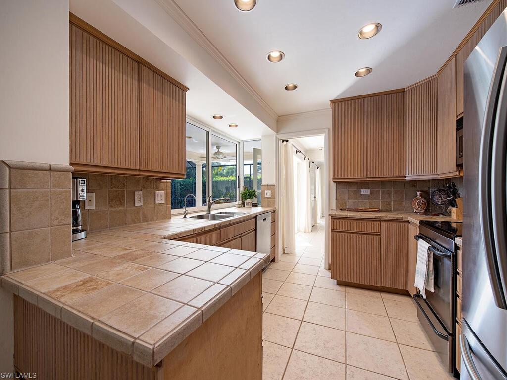 4406 Crayton Road Naples, FL 34103 - Photo 8 of 8 a kitchen with a sink a stove top oven and cabinets
