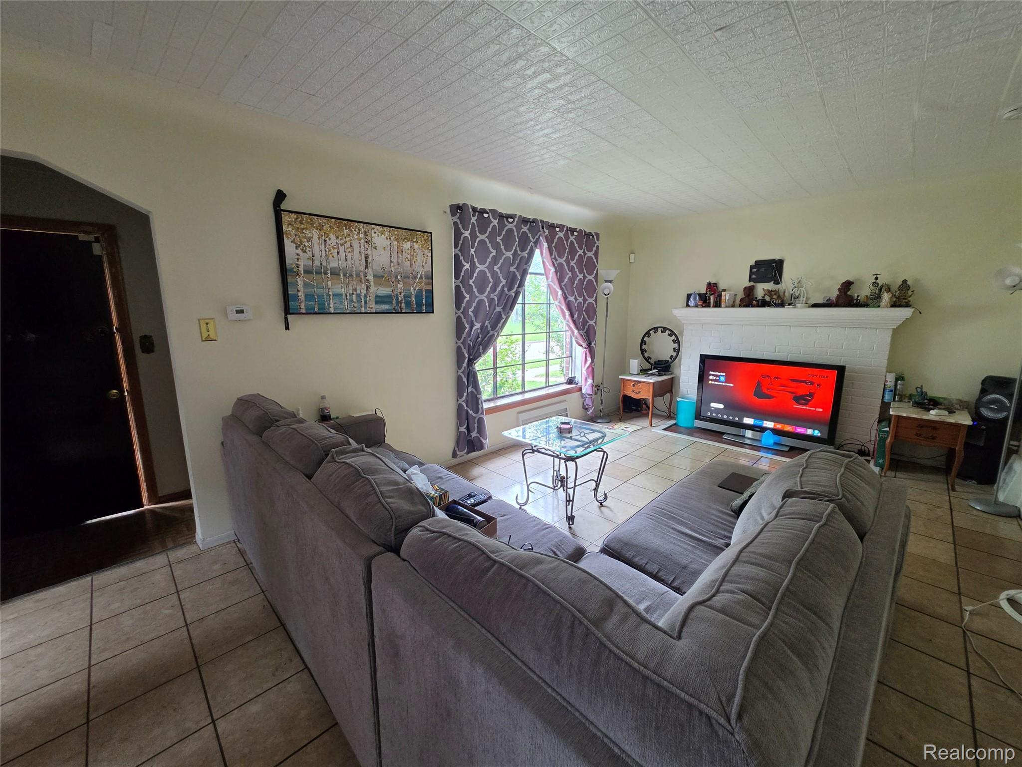 15832 Griggs Street Detroit, MI 48238 - Photo 8 of 24 Living room featuring ceramic tile flooring, a prominent decorative fireplace, a window with natural light, and textured ceiling panels