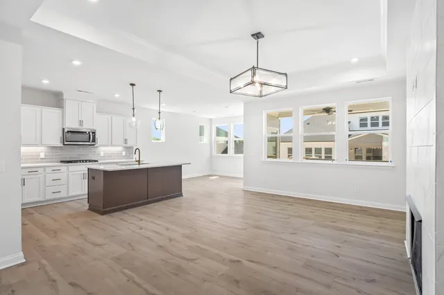 a large kitchen with stainless steel appliances granite countertop a stove a sink dishwasher a refrigerator and a dining table with wooden floor