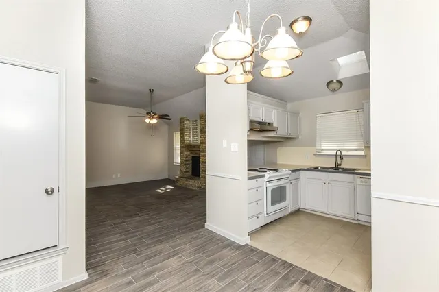 a kitchen with stainless steel appliances granite countertop white cabinets a stove a sink and dishwasher