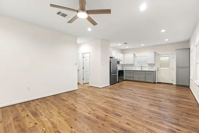 a view of an empty room with kitchen view and a window