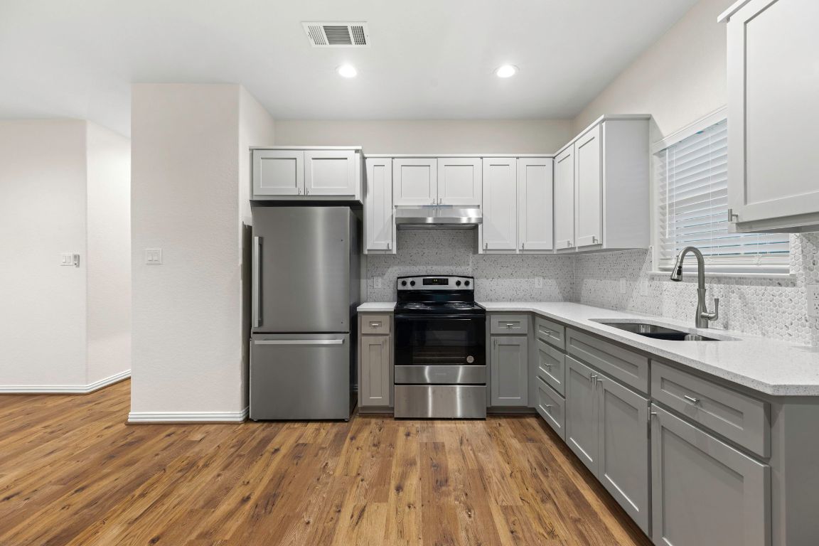 1303 Aransas Street Lockhart, TX 78644 - Photo 7 of 16 a kitchen with a refrigerator a sink and a stove top oven