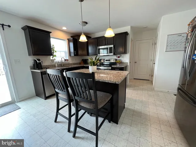 a kitchen with stainless steel appliances granite countertop a stove a refrigerator a oven a sink a dining table and chairs with wooden floor