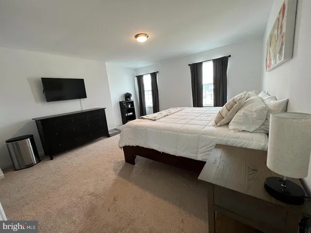 a spacious bedroom with a bed and a flat screen television