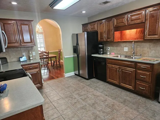 a kitchen with stainless steel appliances granite countertop a stove top oven a sink a counter space and cabinets