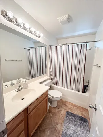 a bathroom with a granite countertop sink a toilet a mirror and a bathtub