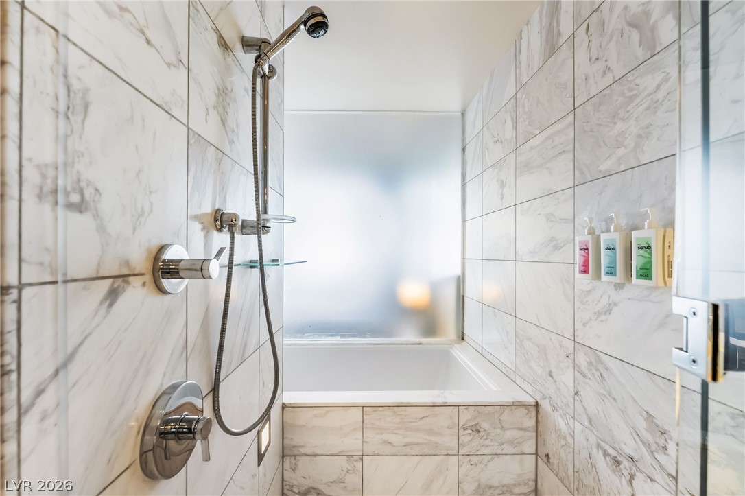 4381 West Flamingo Road, Unit 18305 Las Vegas, NV 89103 - Photo 6 of 19 Marble-tiled shower and tub combination provides a luxurious bathing experience.