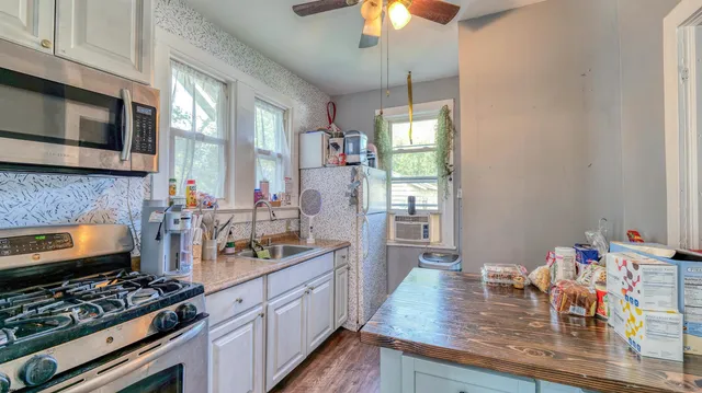 a kitchen with stainless steel appliances a stove a sink dishwasher and microwave with wooden floor